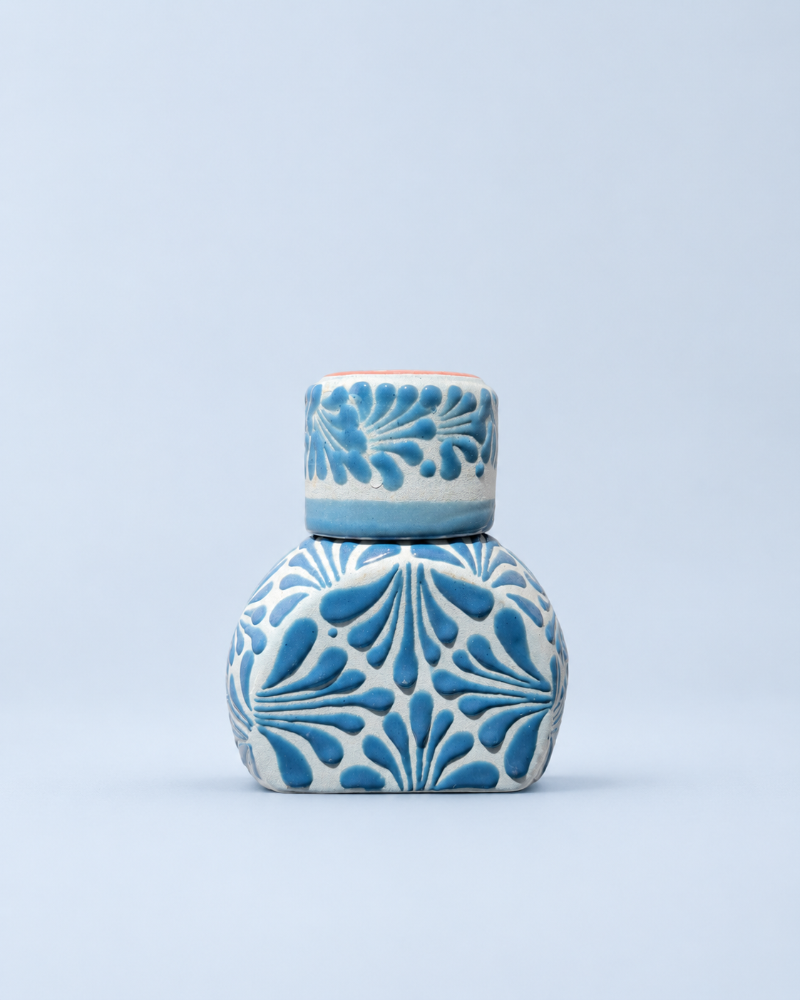 Ceramic liquor bottle with blue floral patterns on a light blue background