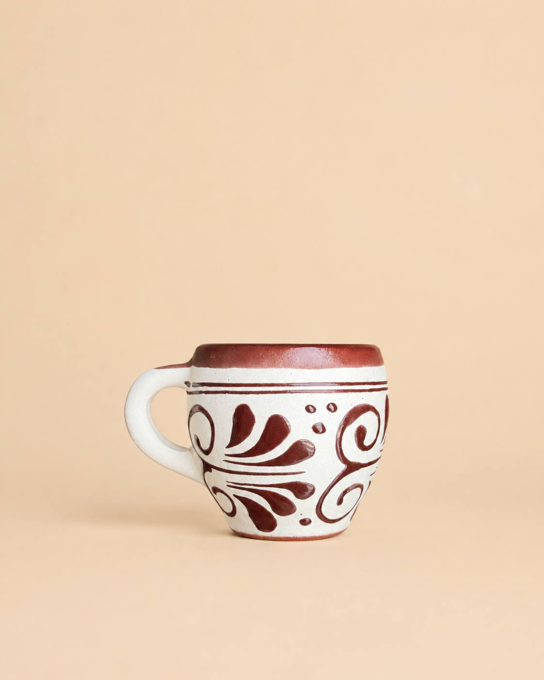 Ceramic mug with brown floral patterns on a beige background