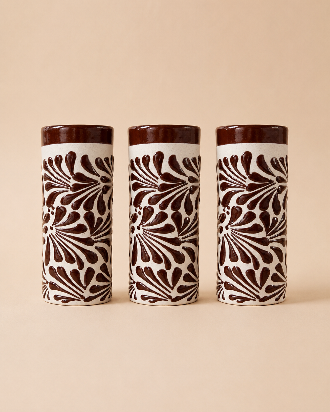 Three ceramic tumblers with brown and white pattern on a beige background