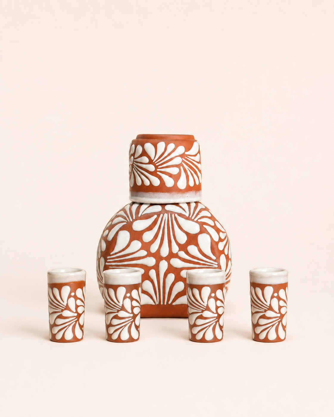 Ceramic set with a large bottle and four smaller cups featuring white floral patterns on a beige background.
