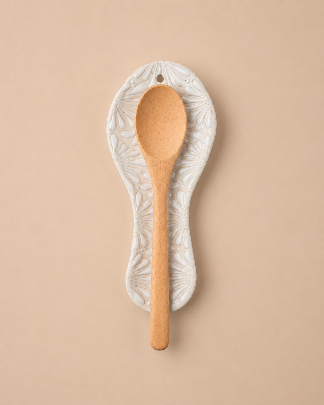 Wooden spoon with decorative white holder on a beige background