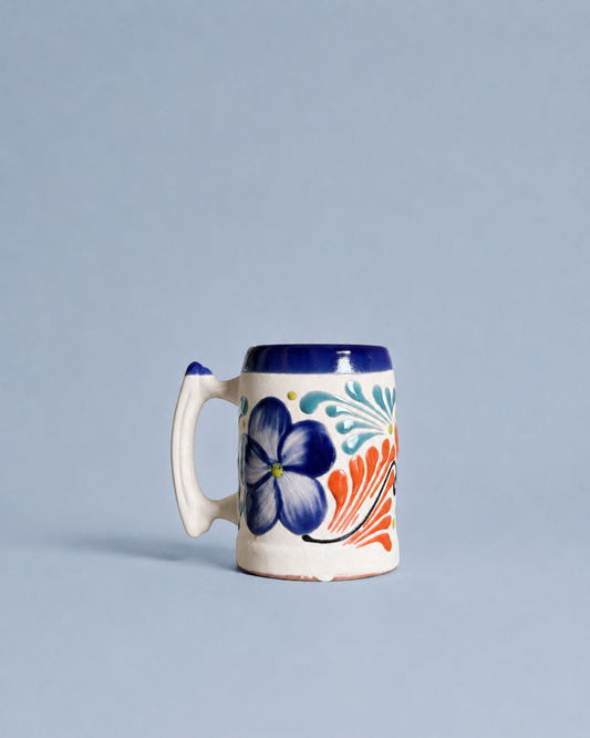 Ceramic beer mug with floral design on a light blue background