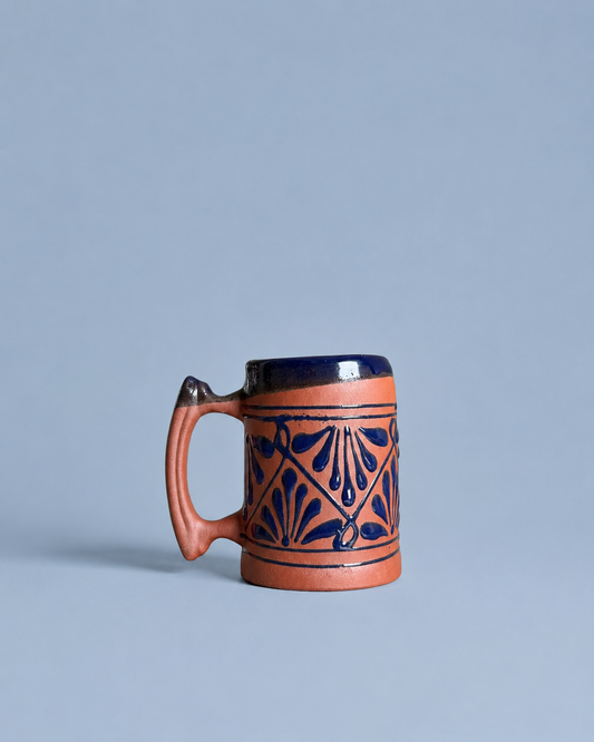 Ceramic beer mug with decorative blue patterns on a light gray background