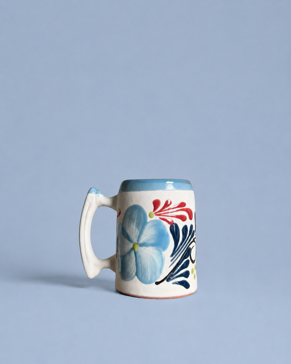 Ceramic beer mug with floral design on a light blue background