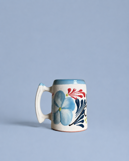Ceramic beer mug with floral design on a light blue background