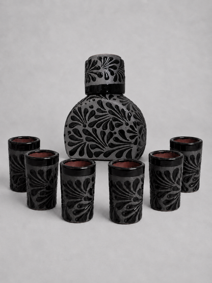 Black ceramic tequila bottle set with intricate designs on a gray background
