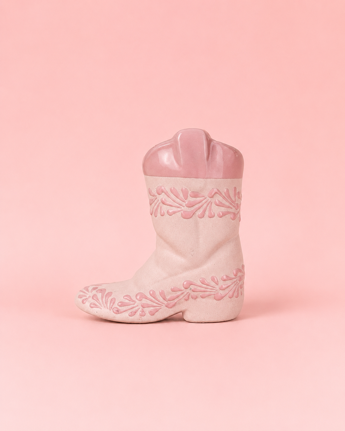 Pink cowboy boot with floral patterns on a pink background
