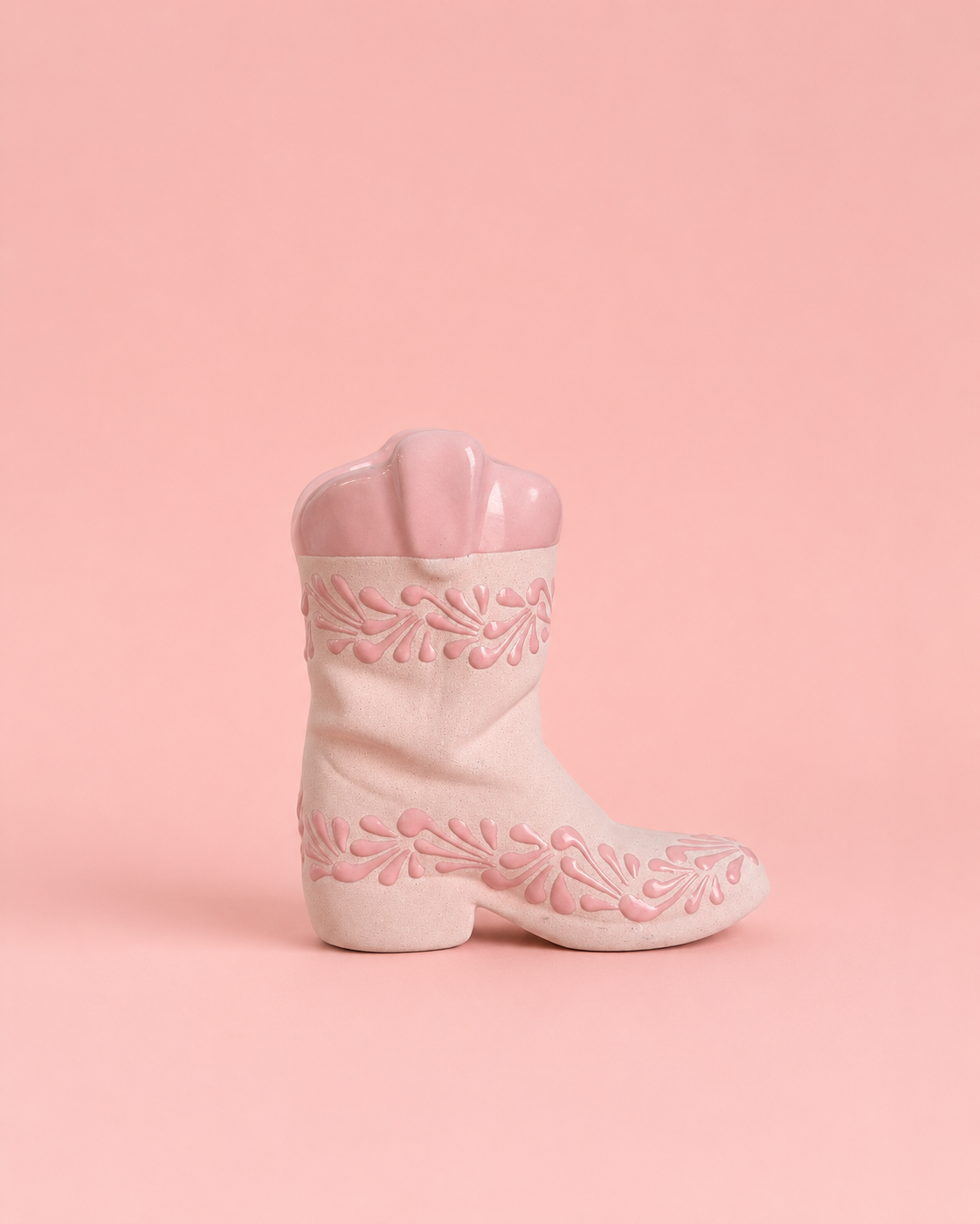 Pink cowboy boot with floral embroidery on a pink background