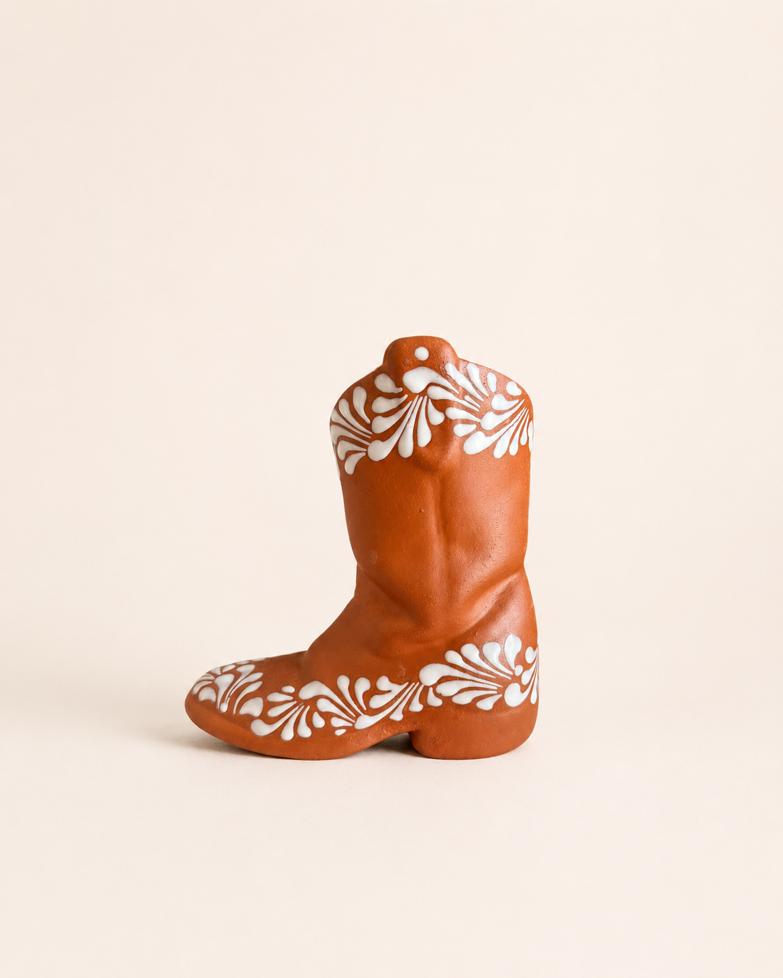 Decorative cowboy boot with white floral patterns on a beige background