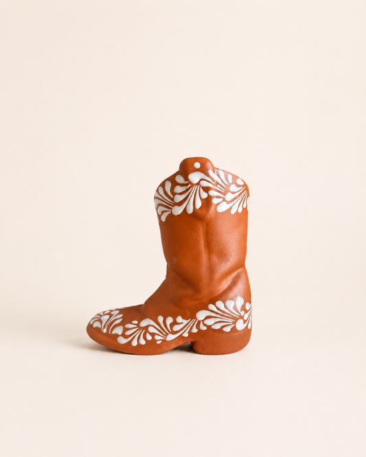 Decorative cowboy boot with white floral patterns on a beige background