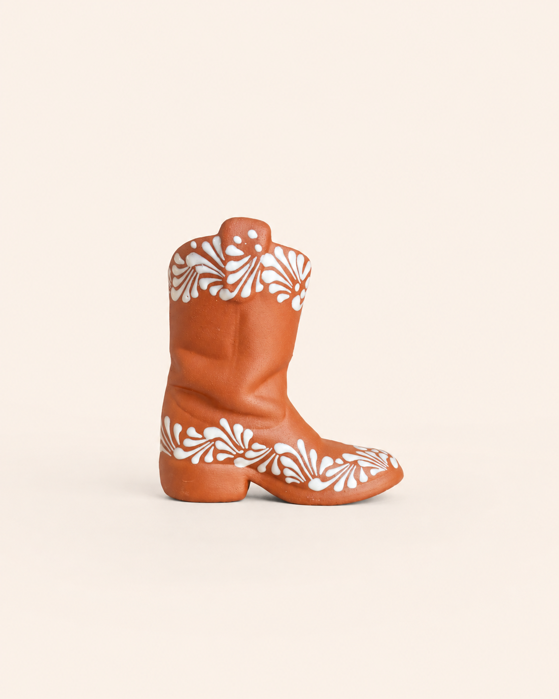 Brown cowboy boot with white floral patterns on a beige background