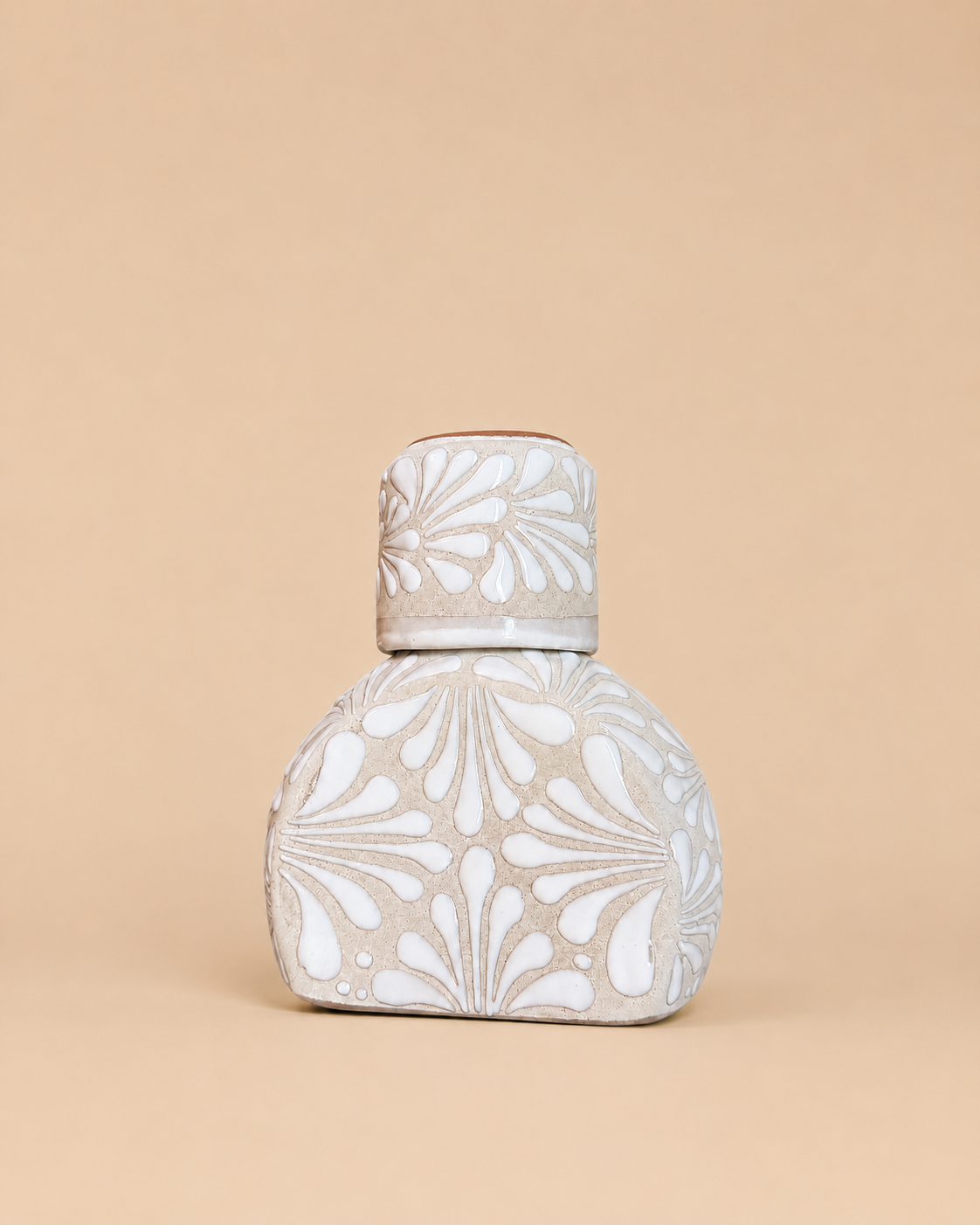 Decorative ceramic liquor bottle with floral patterns on a beige background