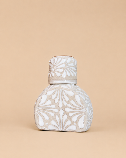 Decorative ceramic liquor bottle with floral patterns on a beige background