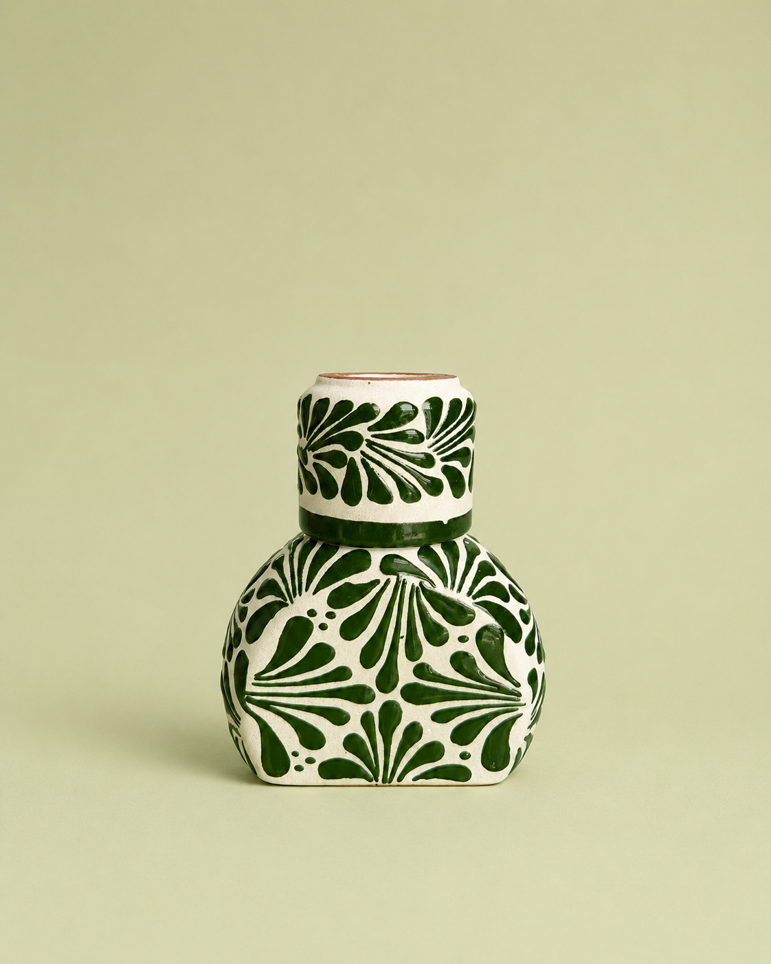 Ceramic liquor bottle with green and white pattern on a beige background