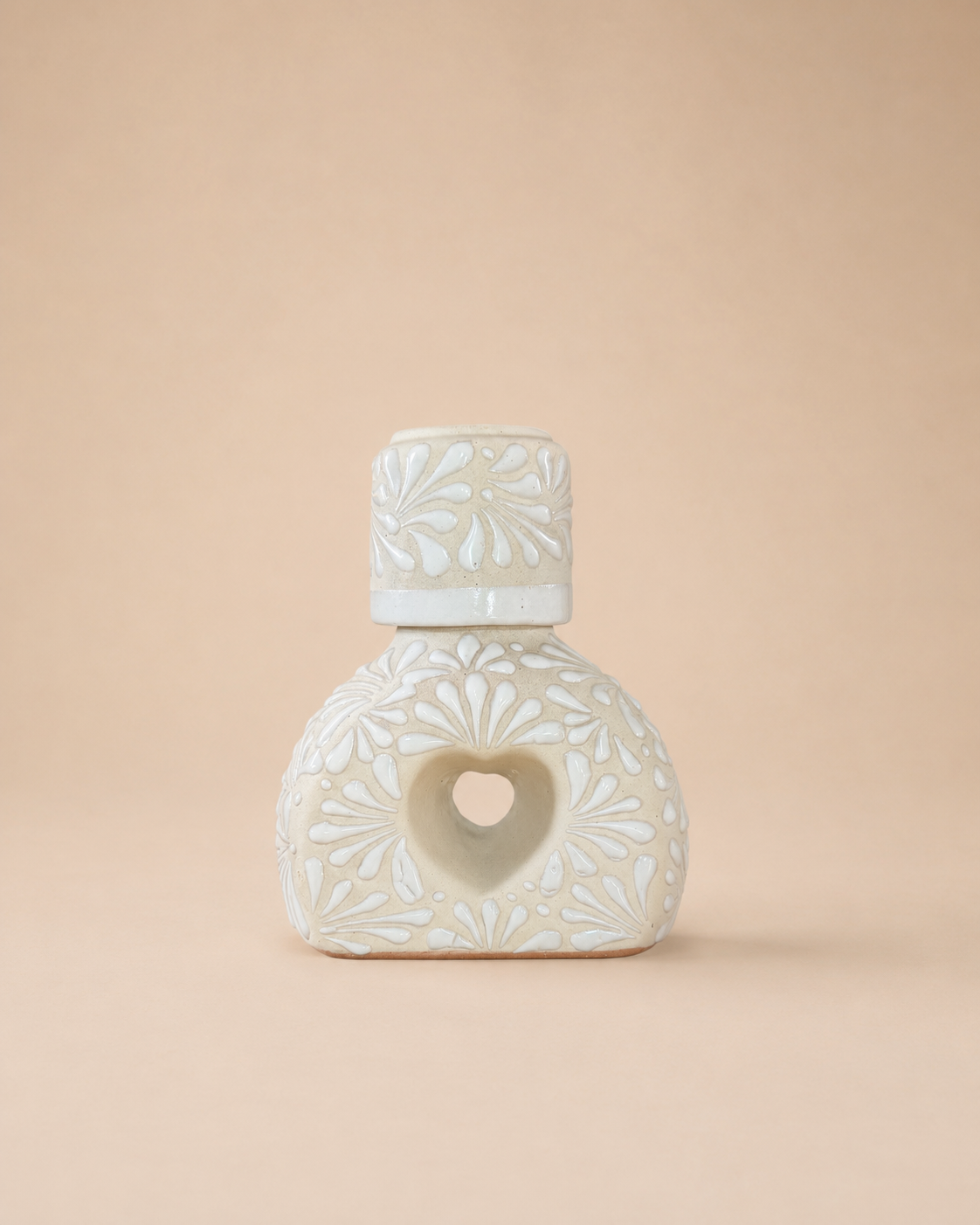 Ceramic liquor bottle with heart-shaped design on a beige background