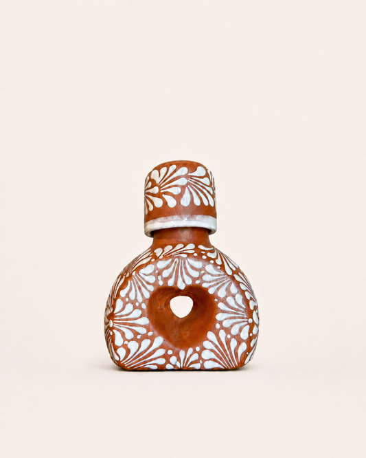 Ceramic liquor bottle with decorative patterns on a beige background