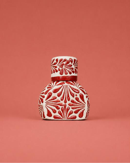 Decorative ceramic liquor bottle with red patterns on a coral background