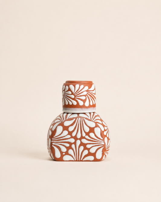 Ceramic liquor bottle with white floral patterns on a beige background