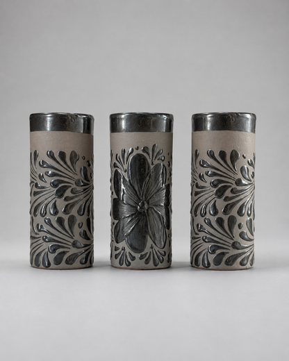 Three cylindrical ceramic cups with floral patterns on a gray background