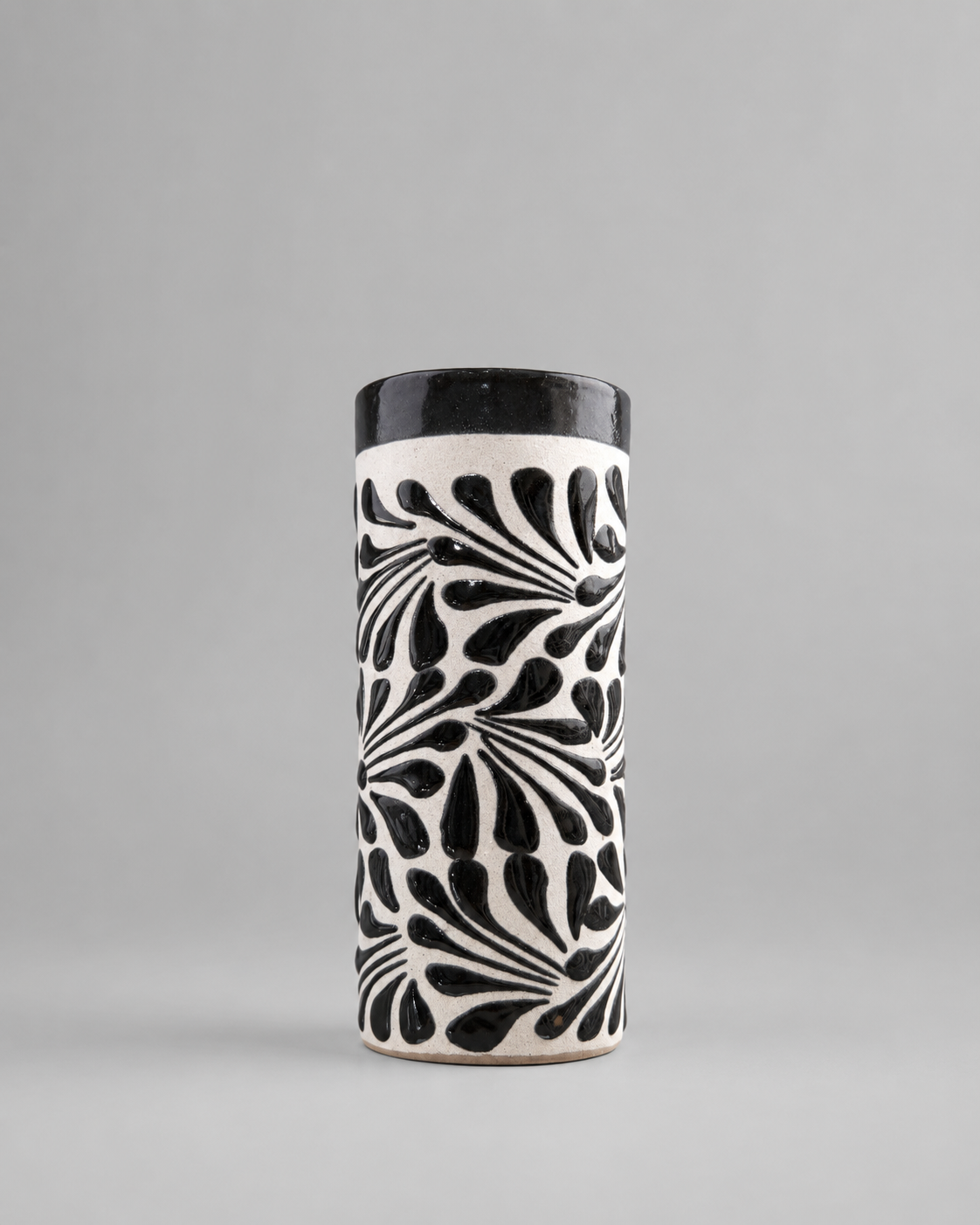 Cylindrical ceramic cup with black and white pattern on a gray background