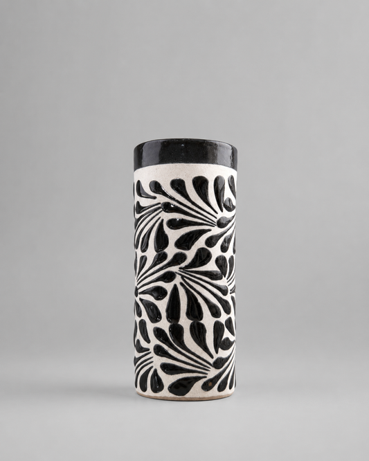 Cylindrical ceramic cup with black and white pattern on a gray background