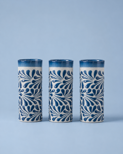 Three ceramic tumblers with blue and white pattern on a light blue background