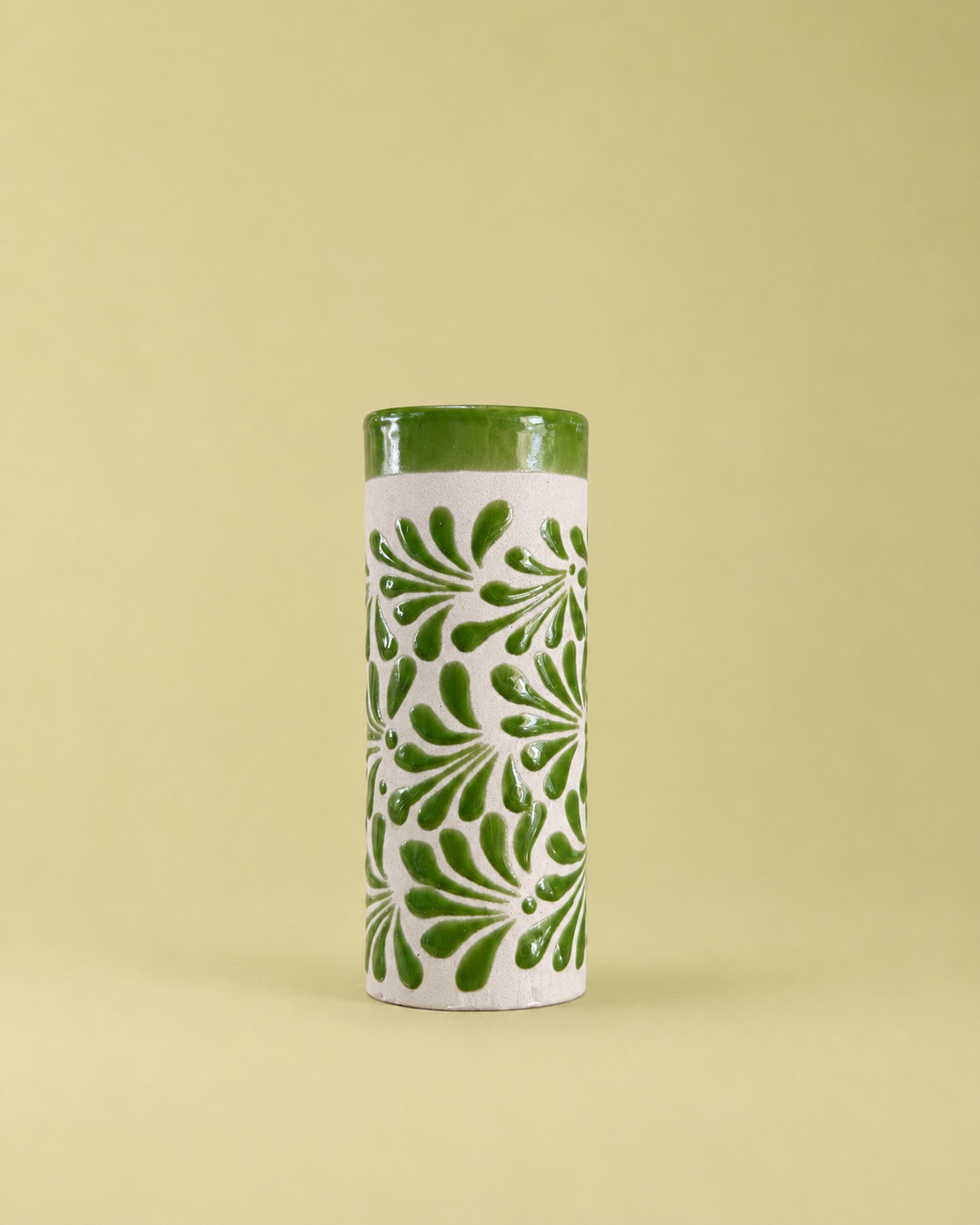 Tall cylindrical ceramic cup with green floral patterns on a light green background