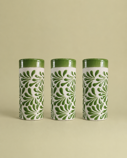 Three cylindrical ceramic cups with green and white patterns on a beige background