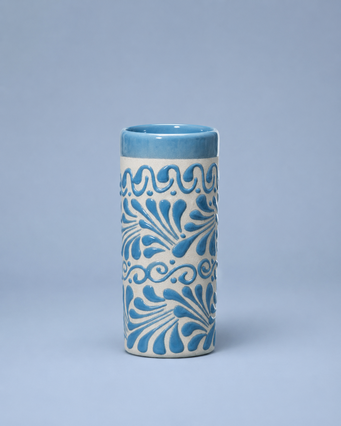 Cylindrical ceramic cup with blue floral patterns on a light blue background