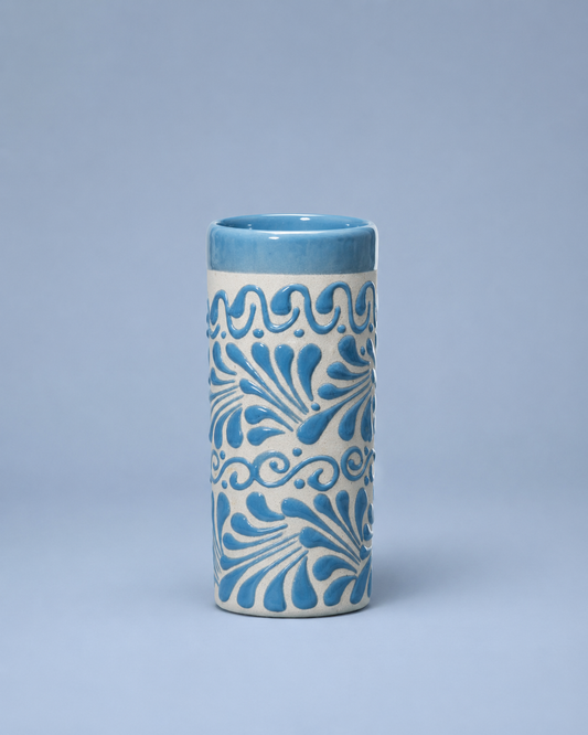 Cylindrical ceramic cup with blue floral patterns on a light blue background