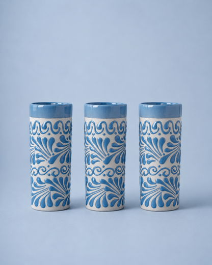 Three ceramic tumblers with blue floral patterns on a light blue background