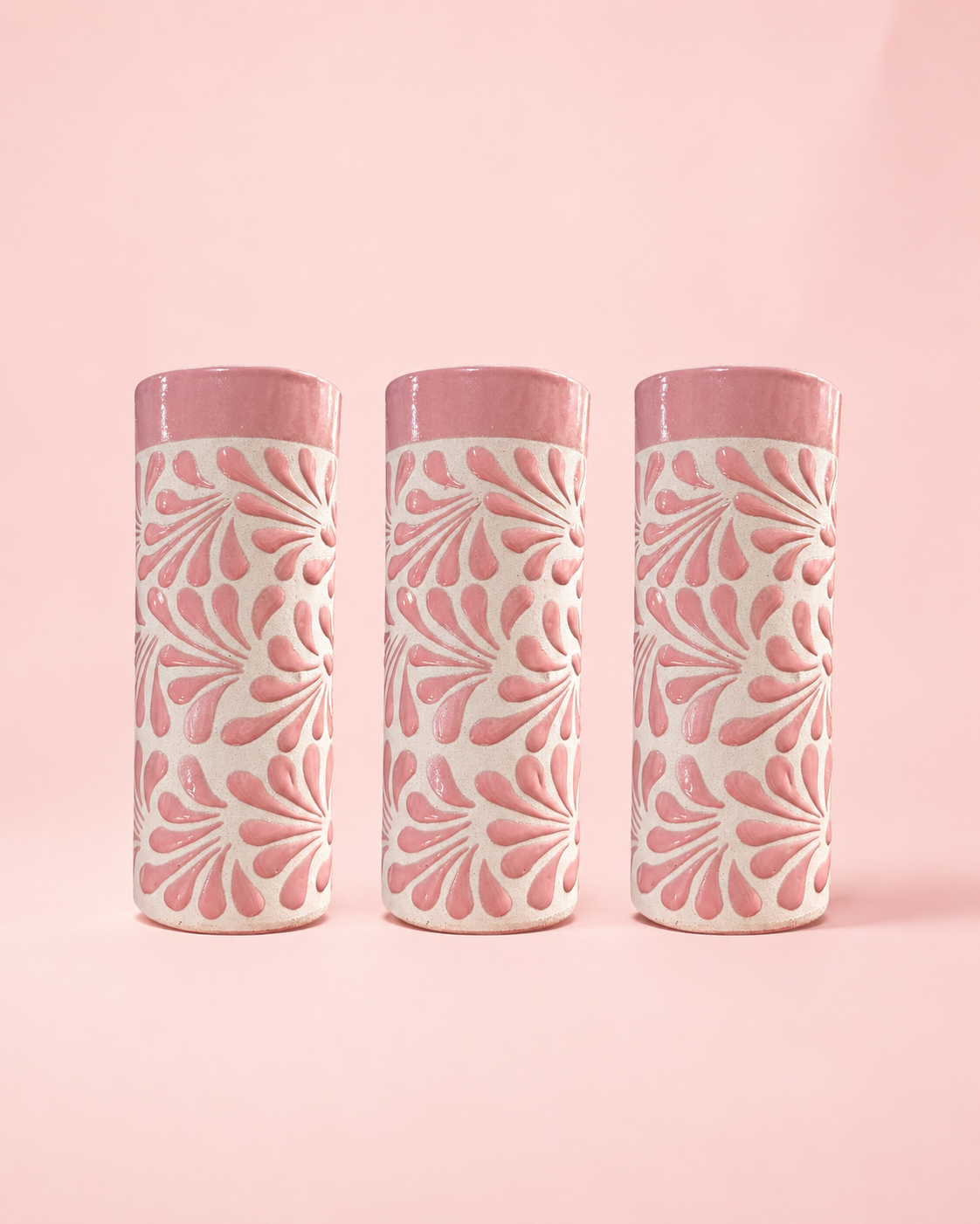 Three cylindrical tumblers with pink and white pattern on a pink background