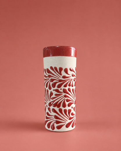Tall cylindrical cup with red and white pattern on a pink background