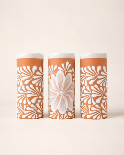 Three cylindrical cups with floral patterns on a beige background