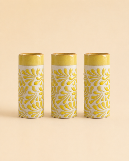 Three cylindrical cups with yellow floral patterns on a beige background