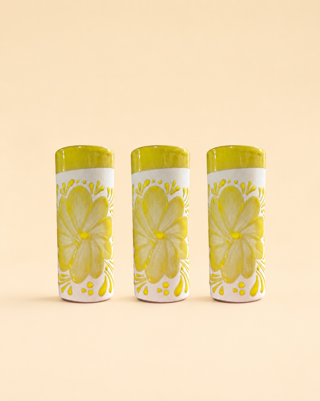 Three cylindrical cups with floral designs on a beige background