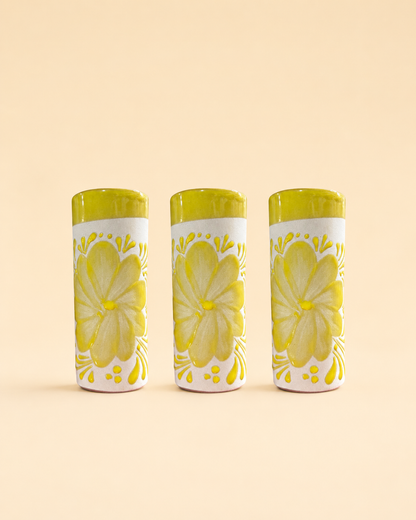 Three cylindrical cups with floral designs on a beige background