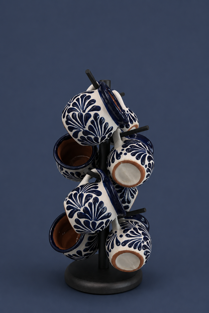 Set of white ceramic cups with dark blue floral patterns on a dark stand against a blue background