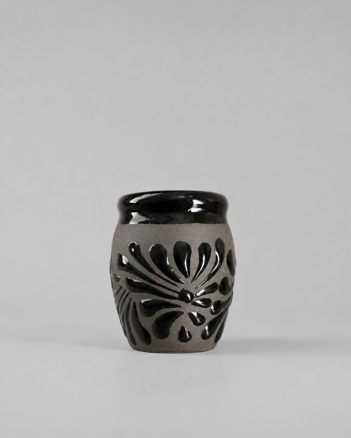 Shot glass with black floral patterns on a gray background
