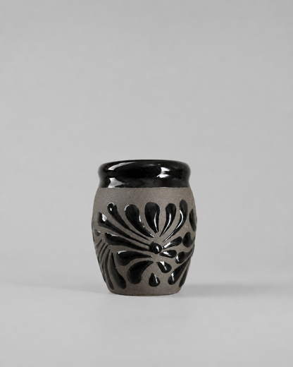 Shot glass with black floral patterns on a gray background