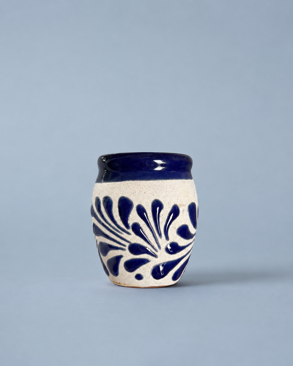 Shot glass with blue floral patterns on a light gray background