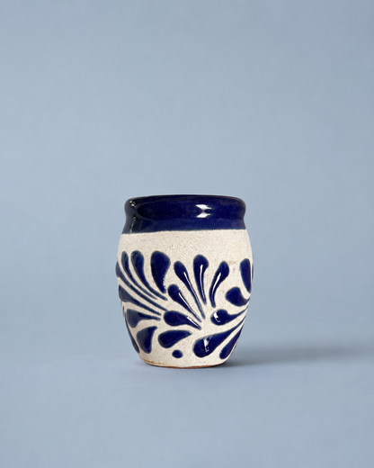 Shot glass with blue floral patterns on a light gray background