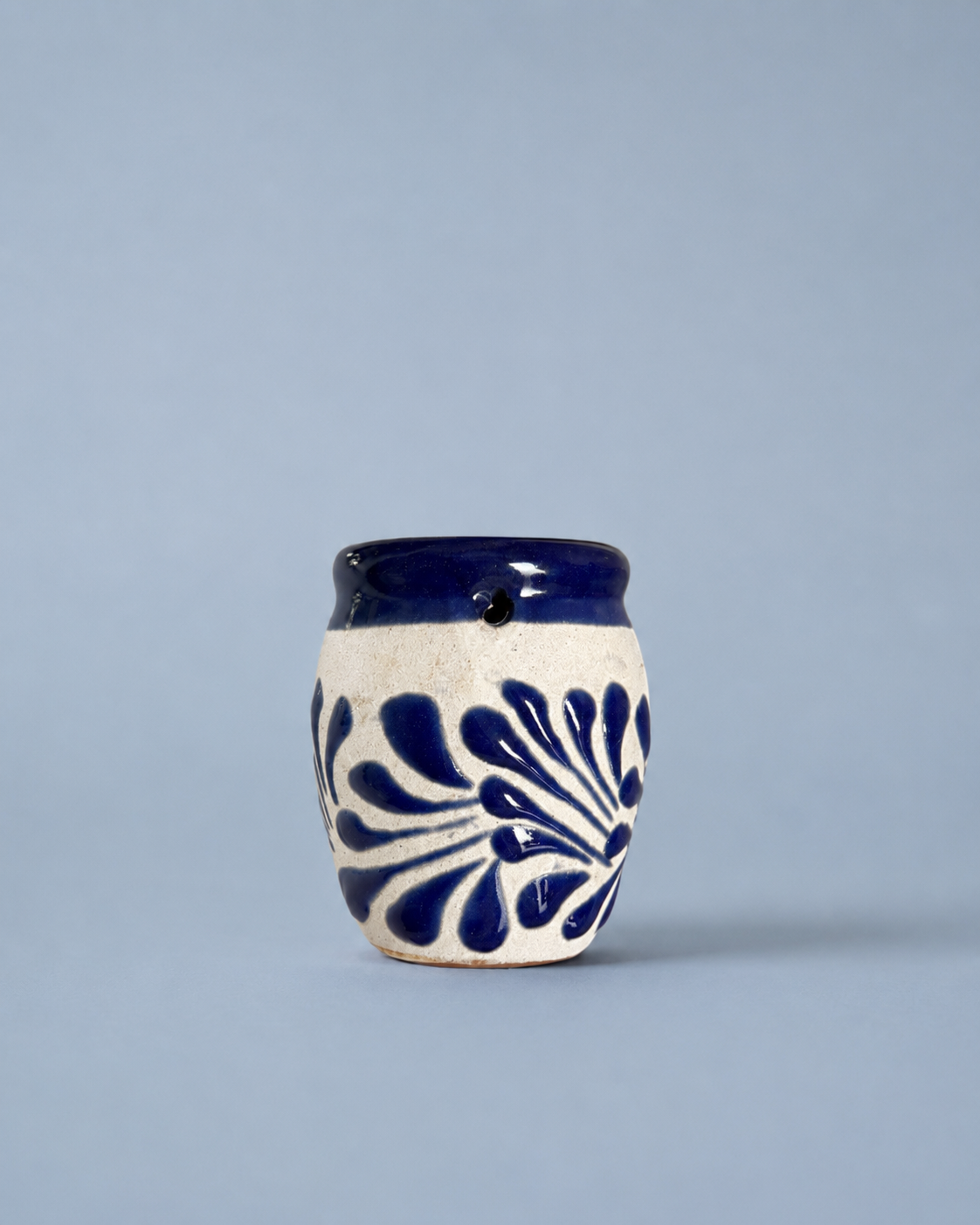 Shot glass with blue floral patterns on a light gray background