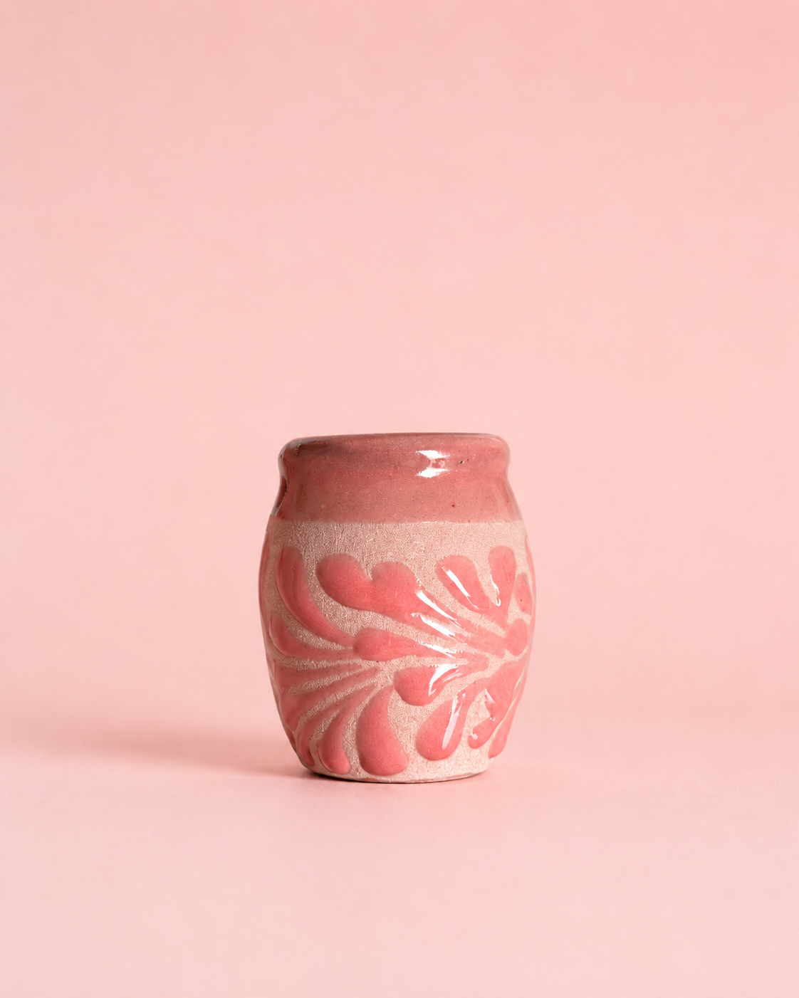 Shot glass with pink floral design on a pink background
