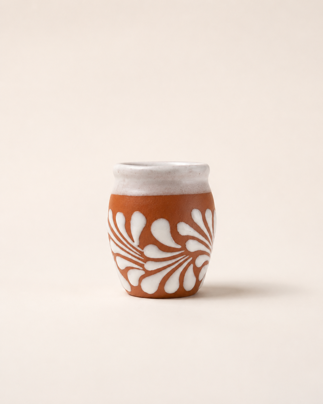 Shot glass with white floral pattern on a beige background