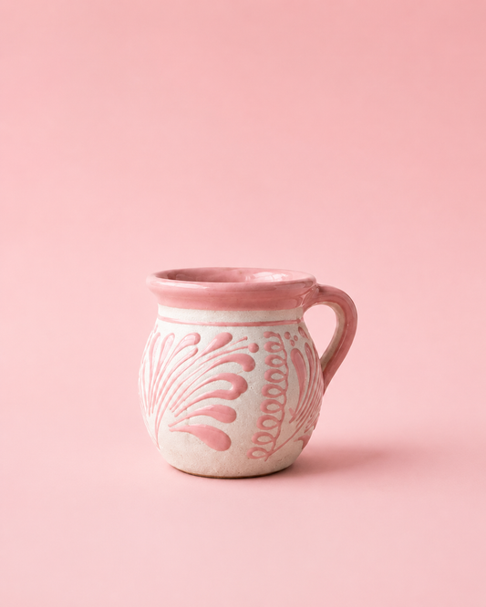Pink ceramic mug with decorative patterns on a pink background