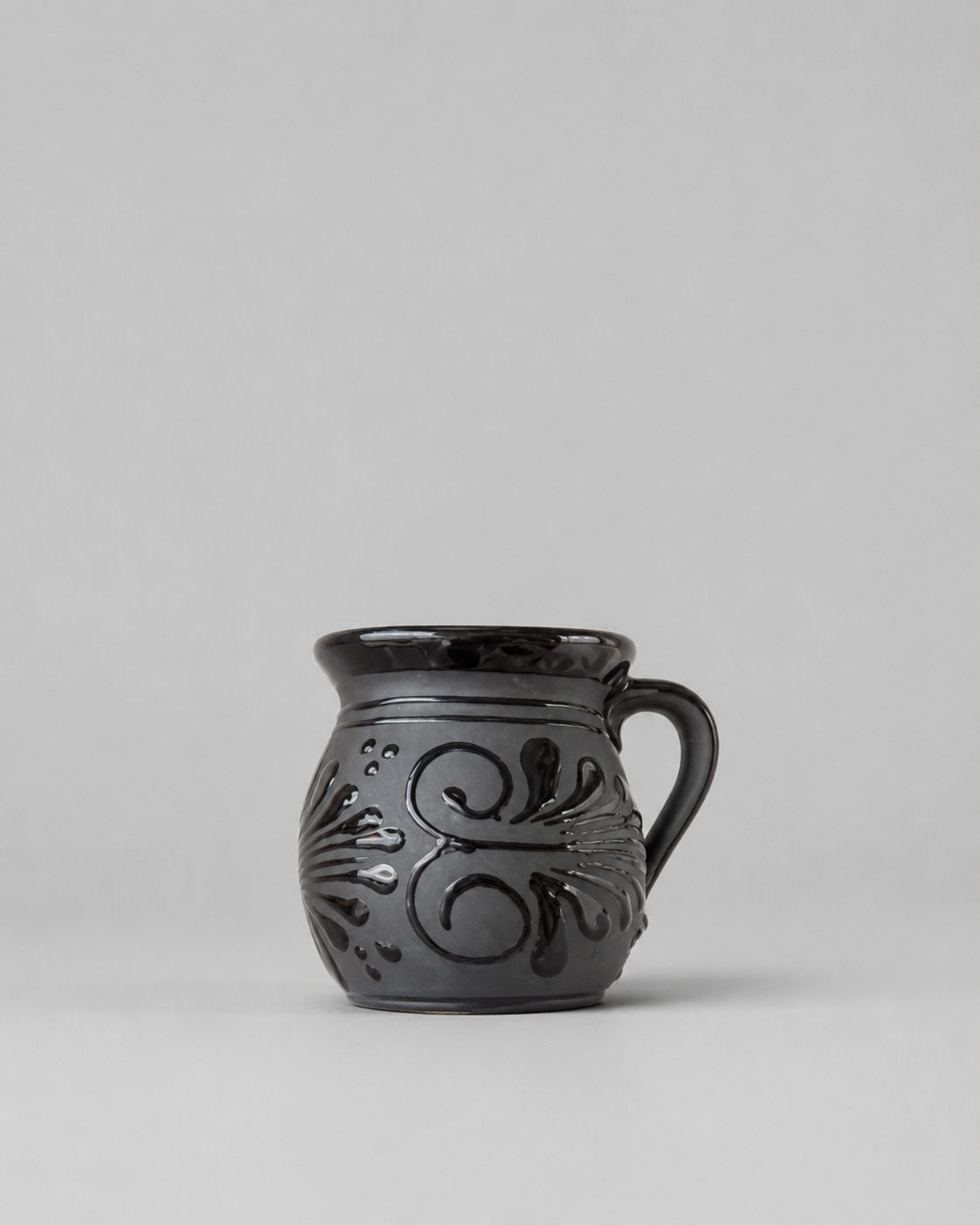Black ceramic mug with decorative patterns on a gray background