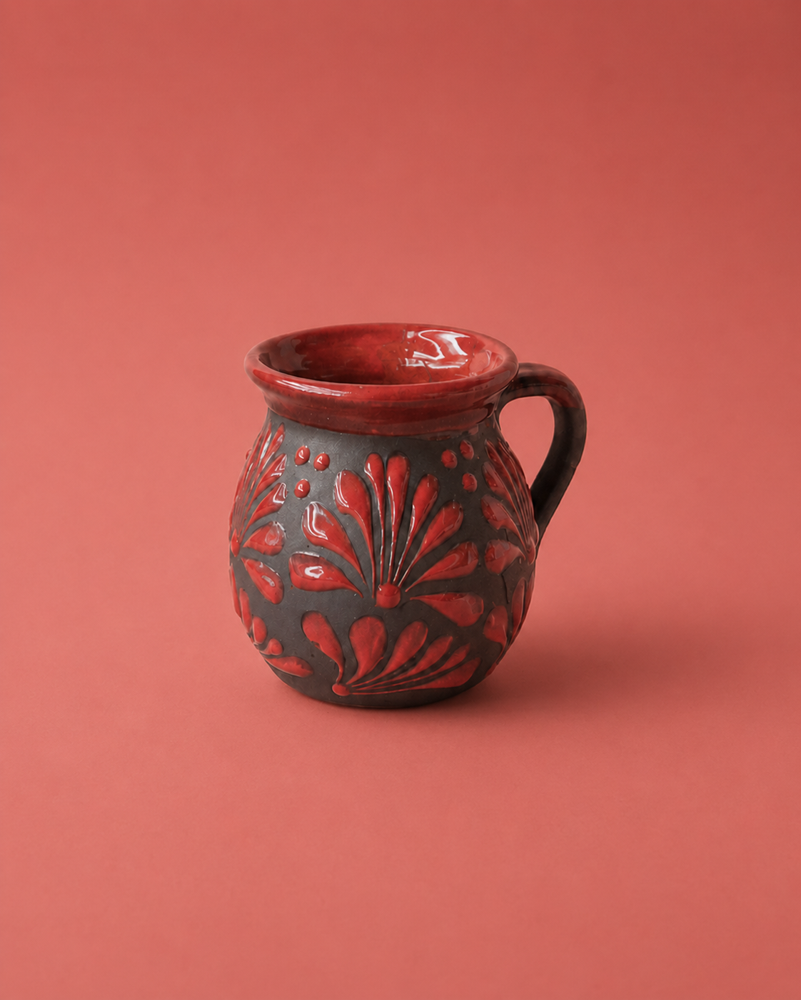 Ceramic mug with red floral patterns on a red background