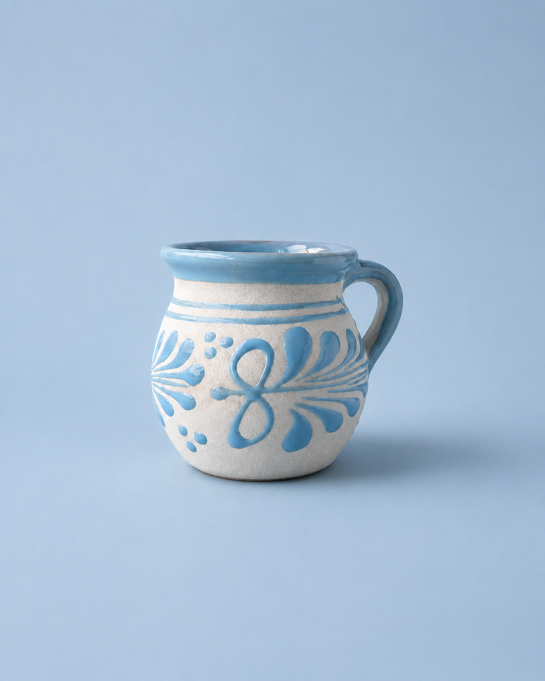 Ceramic mug with blue floral patterns on a light blue background