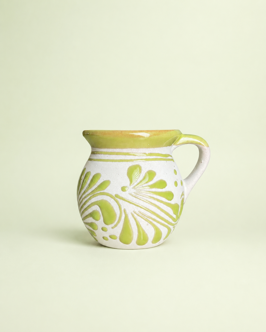 Ceramic mug with green floral patterns on a light beige background